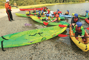 Students sitting on kayaks and listening to JCA instructor